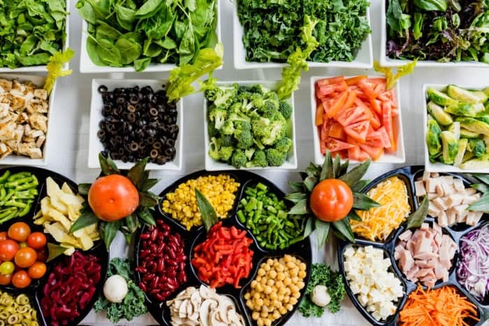 Salad bar with greens, broccoli, black olives, and more