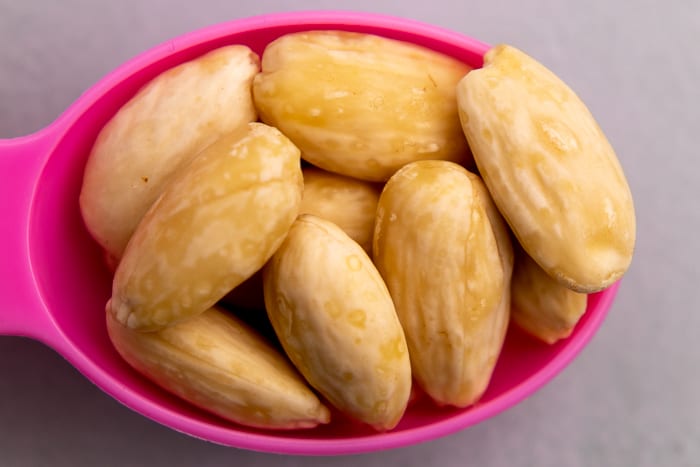 Peeled almonds in a measuring spoon